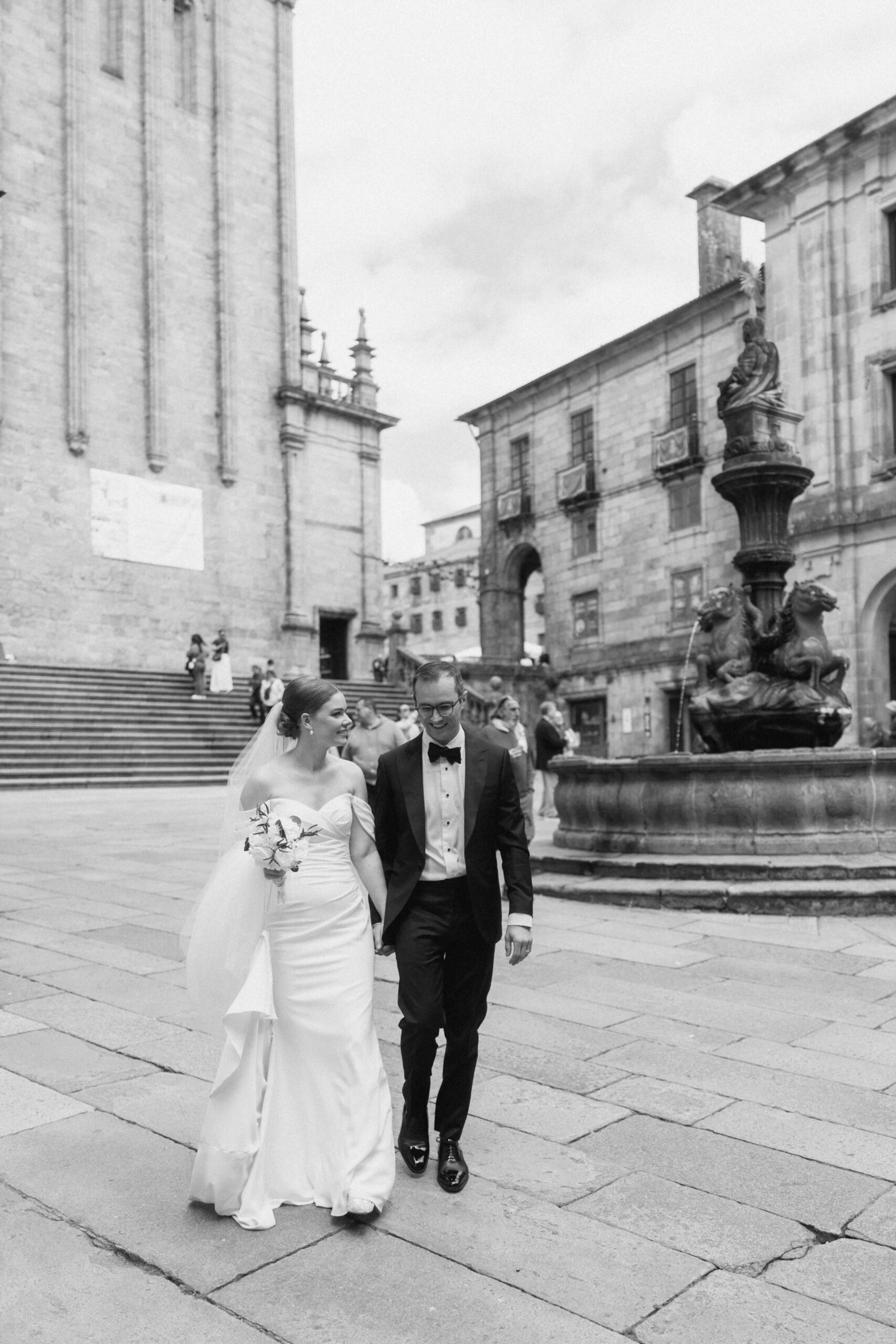 Pareja de novios paseando de la mano junto a una fuente en Santiago de Compostela. plaza de Praterías