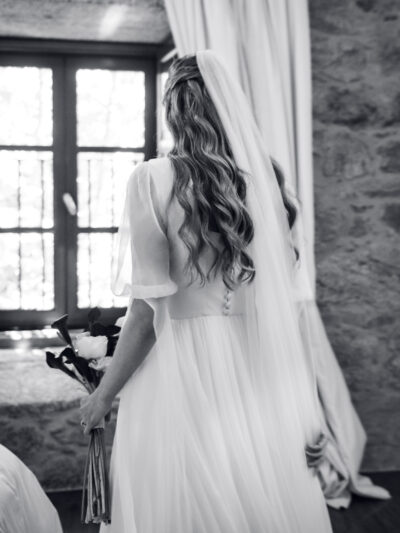 Julia & Aidan | Preparativos de la novia – Destination Wedding Galicia Julia de espaldas, con su vestido de novia, velo y ramo, durante los preparativos de su boda en Galicia.